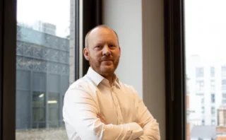 Dan McNally by a window with his arms crossed.