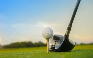 Golf clubs and balls on a green lawn in a beautiful golf course with morning sunshine