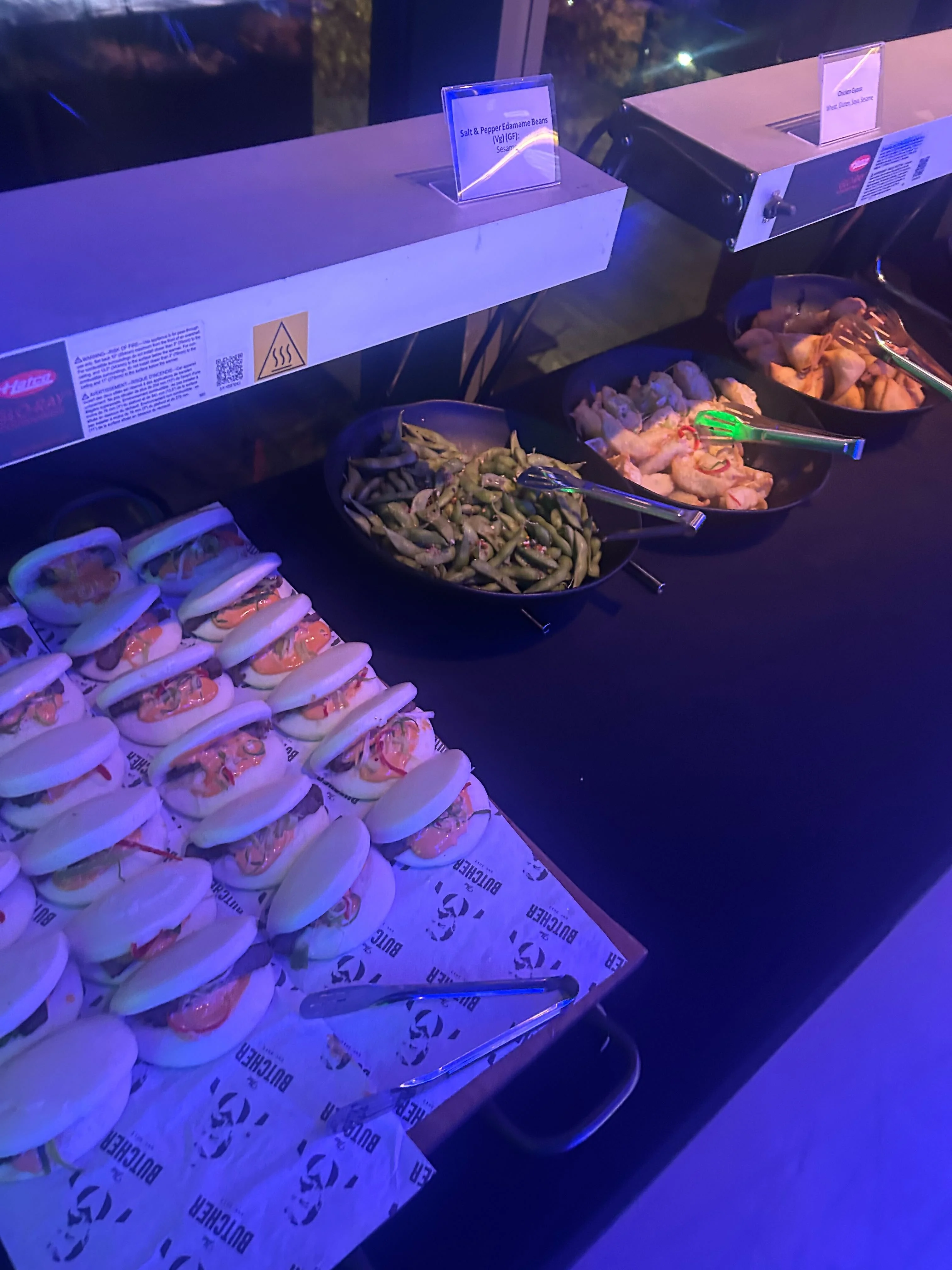 A table with plates of bao buns, edamame, prawns and chicken.